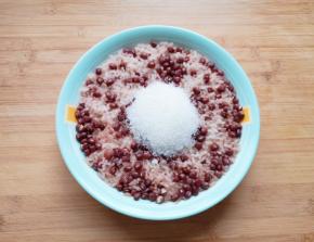 蒸好的糯米红豆从锅里取出，加入糖趁热搅拌均匀。