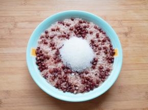 蒸好的糯米红豆从锅里取出，加入糖趁热搅拌均匀。