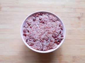 将蒸好的红豆糯米饭装在碗里，用勺子压实。