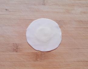 取一个饺子皮，用擀面杖把边缘擀薄。