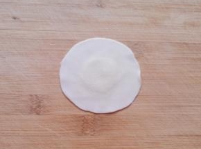 取一个饺子皮，用擀面杖把边缘擀薄。
