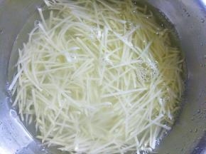 把土豆去皮洗净擦丝后过清水两次，加入热开水烫一下后过凉水待用。