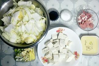 准备食材，白菜切段，豆腐切块，猪肉切片，葱姜蒜切开待用。