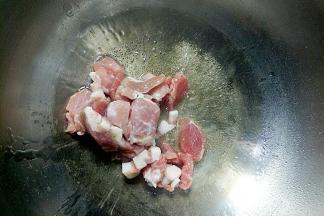 锅中倒入植物油开小火，油温7成热放入猪肉炒至变色。