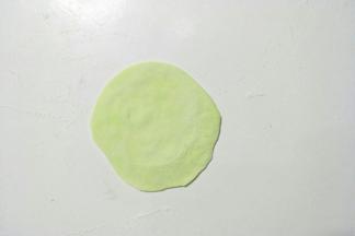 取一个小剂子擀成中间厚周边薄的饺子皮状。