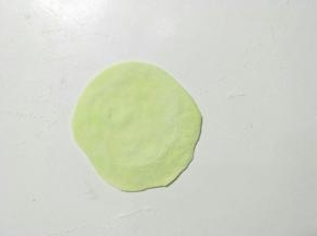 取一个小剂子擀成中间厚周边薄的饺子皮状。