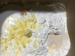把制作面包所需要的材料除黄油外，其它的一同放入面包桶内启动和面程序10分钟，