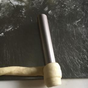 松弛后的面团擀成35-40CM和长条状，卷至学厨模具上，头尾两端贴紧面团以免松开。