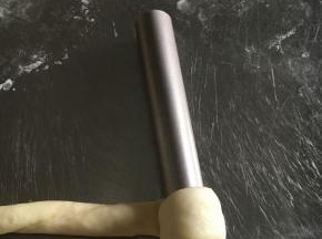 松弛后的面团擀成35-40CM和长条状，卷至学厨模具上，头尾两端贴紧面团以免松开。