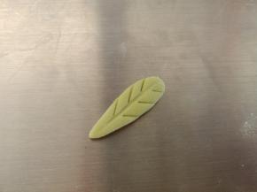 取一个绿色面团，稍微压扁，用小刀压出叶子的纹路，其他的依次做好