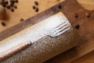 取出蛋糕卷，在蛋糕卷上放一把叉子，筛上防潮糖粉装饰。