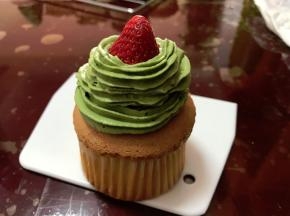 纸杯蛋糕晾凉后，把草莓放在顶部中间，把奶油围着草莓旋转向上挤出圣诞树造型