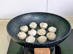平底锅中，刷少许食用油，再摆放上小笼包，盖上盖子小火慢煎。