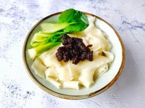 把面条盛入碗里加入牛肉酱与青菜。