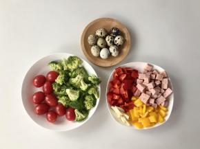 把鹌鹑蛋煮熟，红椒和黄椒洗净切成丁，午餐肉切成丁，大蒜切片，西兰花洗净切成小朵，圣女果洗净。（一份便当不会用到图中这么多，可以多做几份）
