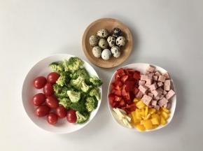 把鹌鹑蛋煮熟，红椒和黄椒洗净切成丁，午餐肉切成丁，大蒜切片，西兰花洗净切成小朵，圣女果洗净。（一份便当不会用到图中这么多，可以多做几份）