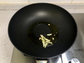 先来做配菜，锅里热油，下入蒜片爆香。