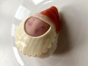 取一个即食的蟹肉棒，冷冻的需要蒸熟或烫熟。把红色的表皮揭下来，贴在饭团的上半部分做帽子，边缘可以用一小截意大利面固定。