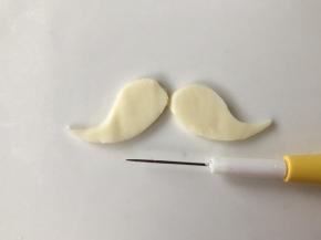 用翻糖针在芝士片上画出人中部分的胡子。或者用烘焙纸画好形状后，放在芝士片上，一起用剪刀剪出胡子的形状。