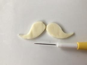 用翻糖针在芝士片上画出人中部分的胡子。或者用烘焙纸画好形状后，放在芝士片上，一起用剪刀剪出胡子的形状。