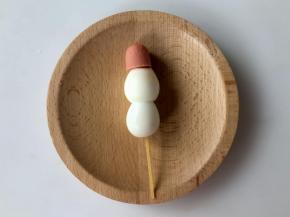 接着我们来做小雪人，把两个鹌鹑蛋尖的一端切平，用意大利面串在一起，然后切下火腿肠的另一端，插在鹌鹑蛋上，做小雪人的帽子。