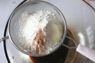 5、一部分低筋面粉，肉桂粉，过筛到刚才搅匀的液体中。稍微拌一下，再筛入全部的低筋面粉。用刮刀把液体和粉类拌匀。