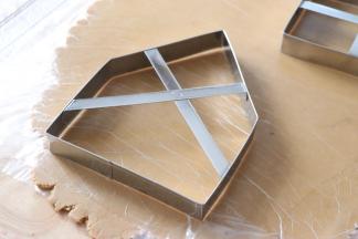 擀好之后，用模具切出形状。剩余的边角料，收拢起来，另外一个面团，也擀成同样薄厚的面片，用模具切出形状。边角料再继续揉成团后，切出形状。最后剩余的可以做成姜饼屋的底。