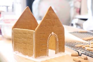 我没有制作饼干底，用了纸托，首先把需要和底部连接的部位，挤上糖霜，房子需要连接的部位也挤上糖霜，之后把房子的形状拼起来。门可以装饰一下，之后等待糖霜变干。房子结构没有牢固的时候，先不要安装房顶。