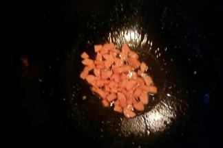 锅中倒油开中火，油温七成热放入火腿丁炒至表面金黄色。