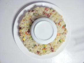 把炒好的米饭盛在碗周围，用勺子压成花环的形状即可。