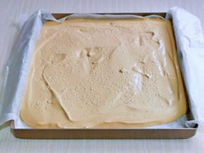 拌好的蛋糕糊，倒入垫有油纸的烤盘中，均匀撒上白芝麻，轻轻震出气泡。