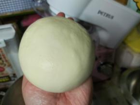 然后暂停机器，加入软化好的黄油跟玫瑰海盐，如果桶壁上有粉类残留，用刮板刮下来，再次启动厨师机15分钟左右，面团基本就可以扯出较为结实的薄膜了，且面团光泽油亮却不会粘手。