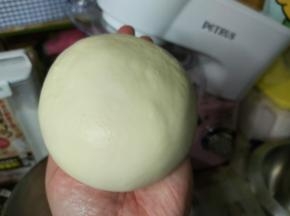 然后暂停机器，加入软化好的黄油跟玫瑰海盐，如果桶壁上有粉类残留，用刮板刮下来，再次启动厨师机15分钟左右，面团基本就可以扯出较为结实的薄膜了，且面团光泽油亮却不会粘手。