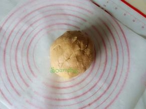 搅拌好的面团分2小团，取一小团放在硅油纸上，然后用擀面杖擀薄至0.5厘米左右。硅油纸的大小和烤盘一致，可以直接放入烤盘。