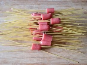 将香肠每根都切成3段，每段都串入4-5根干意面；