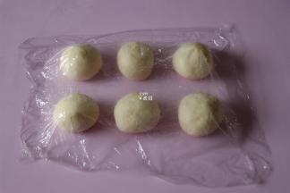 发酵好的面团排气后分割成50g一个的面团，包上紫薯馅收紧收口后揉圆，盖上保鲜膜松弛15分钟；