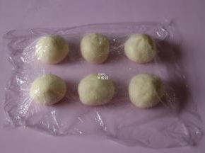发酵好的面团排气后分割成50g一个的面团，包上紫薯馅收紧收口后揉圆，盖上保鲜膜松弛15分钟；