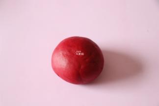 在剩下的面团中倒入甜菜根粉，揉均匀成一个红色的面团；