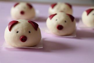 在面团表面相关部位抹少许水，粘上鼻子、耳朵、尾巴、黑芝麻，用牙签在鼻子部位戳2个洞；