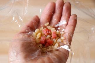 保鲜膜上放一勺米饭，再放适量切碎的香肠；