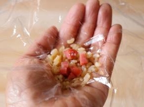 保鲜膜上放一勺米饭，再放适量切碎的香肠；