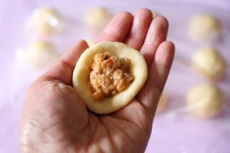 取一个面团，压扁后包入适量肉松，收紧收口滚圆，全部包好后盖上保鲜膜二次发酵30分钟；