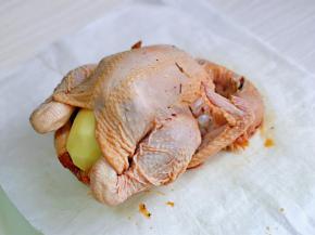 第二天取出腌制好的鸡，肚子里塞入一个去皮的土豆，放在油纸上，包起来。