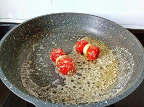 熬好的糖稀撒一点熟的白芝麻，继续开小火【糖稀凉了就裹不上了】放入山楂裹一圈，裹的速度要快、不然糖稀继续加热就变成糖霜了。