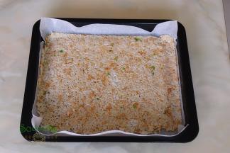 烤盘垫上硅油纸，把保鲜袋用剪刀剪开，擀薄的米饭放入烤盘。