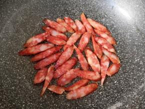 炒锅烧热倒入少许食用油，下入腊肠片小火煎熟，盛出备用。