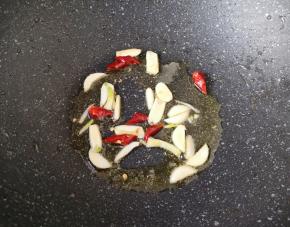 锅底留余油，下入大蒜和干红辣椒炒香。