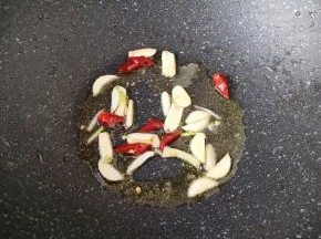 锅底留余油，下入大蒜和干红辣椒炒香。