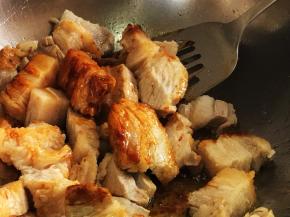 放入五花肉翻炒入糖色，多炒制一小会，煸出肉里多余的油脂。