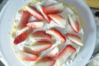 把蛋糕胚横切开，中间涂一层奶油，放入草莓块。